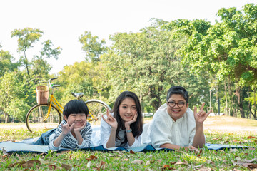 Happy family grandmother daughter and grandson laying down and doing I love you in hand sign language with smiling in park. Happy family concept