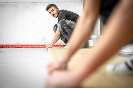 Zwei Parkettleger arbeiten im Team und verlegen einen Eichenboden