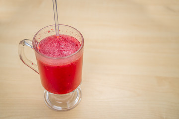 A glass full of blueberry juice placed on a wooden surface.