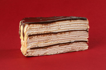 Chocolate crepe layer cake slice red background