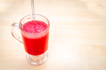 A glass full of blueberry juice placed on a wooden surface.