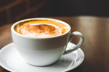 close up modern hot black coffee the cappuccino on wood background with coffee bubble foam pattern and texture in white cup looking and feel so delicious on glasses table in coffee shop.