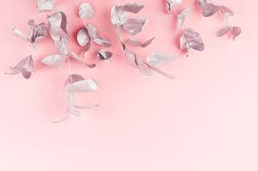 Christmas festive decoration - silver branches and leaves on pastel pink background, top view, copy space.