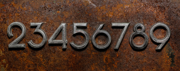 Backgrounds and textures: assorted metal digits on a rusty background, typographic art abstract