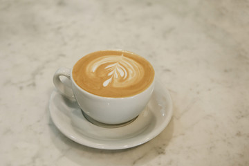 A cup of fresh tasty cappuccino coffee on a marble table.