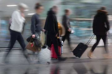 Naklejka premium People with suitcases in blurred motion at airport or railway station