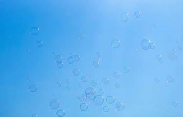 Background with soap bubbles on bright blue sky