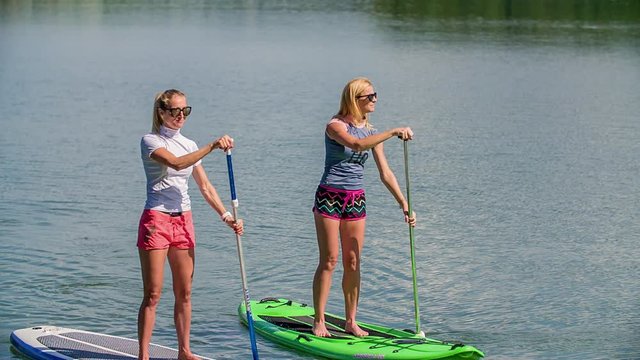 Two women paddle on sup on Smartinsko lake. Slow motion