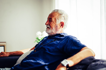 Senior man sitting alone for relaxation and smile portrait in home.