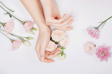 Beautiful stylish trendy female pink manicure with flower on background, top view. Concept bio nature cosmetics skin care