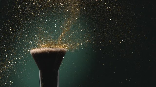 Glitter on a Make-up Brush Flying Away with Woman Finger Flicking Shot in Slow Motion on Green Aqua Menthe Color Background