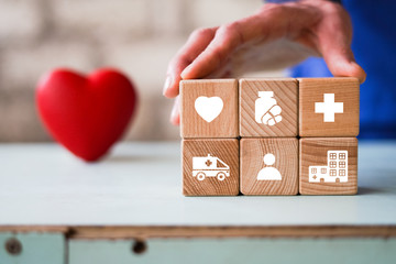 Doctor hand arranging wood block stacking with healthcare icons, insurance for your health, on the background of the heart.