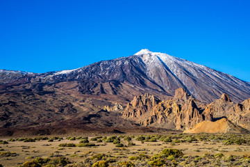 Spain, Tenerife, Rocky caldera desert surrounding snow covered summit of mountain teide volcano in...