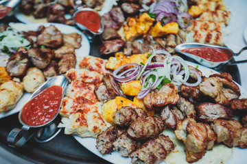 Variety assortment of traditional main course meat barbecue grill dishes of Caucasian cuisine, with shashlik on skewer, Lyulya kebab, kebab, Azerbaijani cuisine