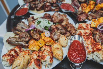 Variety assortment of traditional main course meat barbecue grill dishes of Caucasian cuisine, with shashlik on skewer, Lyulya kebab, kebab, Azerbaijani cuisine