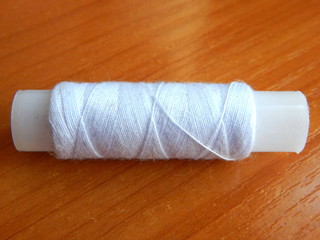 Spool of white thread on the table close up