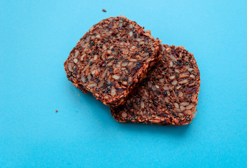 Sliced whole grain bread rye with seeds flax, sunflower, pumpkin and sesame.Healthy food, eco-friendly natural products. Fresh bread on a blue background.