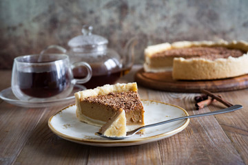 A piece of delicious pumpkin pie with chocolate chips on a beautiful white plate with a spoon on an old wooden background