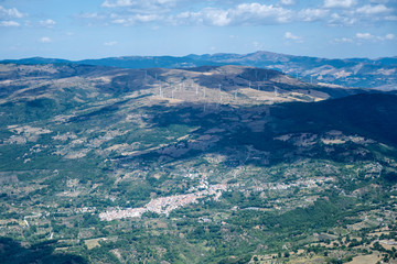 aerial of Montemurro village and wind farm on hill from east, Italy