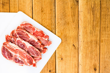Pork chops on a white cutting board over wooden table, meat for bbq, top view, copy space, barbeque...