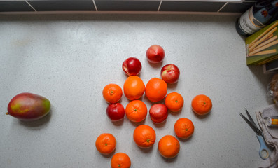 Four fruits: mangoes, oranges, tangerines and peaches (nectarines) on a table 