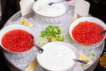 Red caviar and sour cream in ice vase, served with pancakes