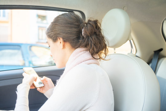 A Young Woman In The Co Pilot Seat In A Car Texting With The Mobile Phone