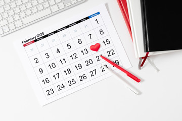 Valentine's Day background. Office table. Date February 14 on calendar 2020, Valentine's Day red heart circled. Flat lay, top view, copy space 