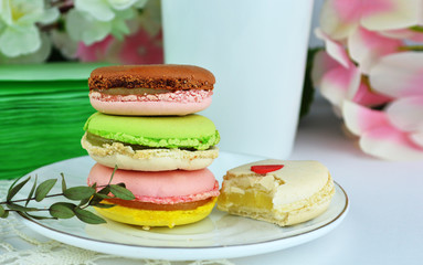 Colorful macaroons on a white plate.  Sweet macarons and flowers. Holiday time concept