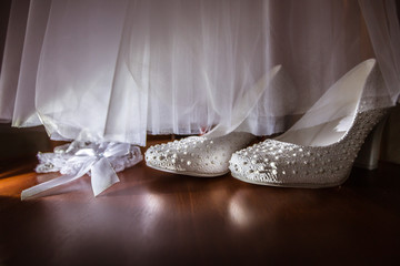 white wedding dress and shoes and garter on black background