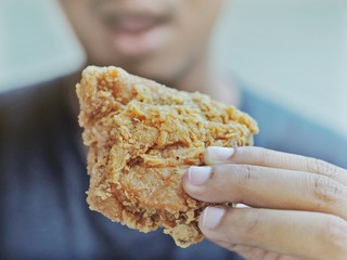 The man he eating a chicken fried.