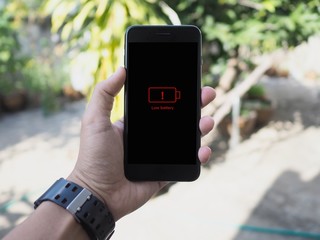 Close up short hand holding low battery smart phone.