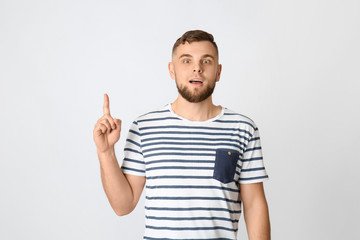 Naklejka premium Emotional young man pointing at something on grey background