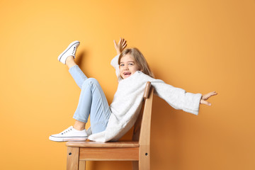 Happy fashionable girl sitting near color wall