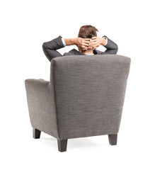Businessman sitting in armchair on white background, back view