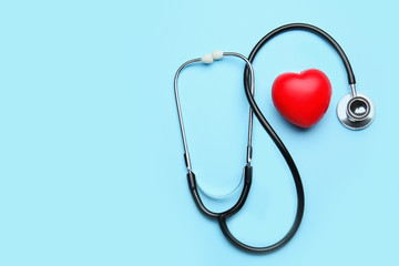 Stethoscope and heart on color background