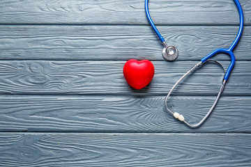 Stethoscope and heart on wooden background