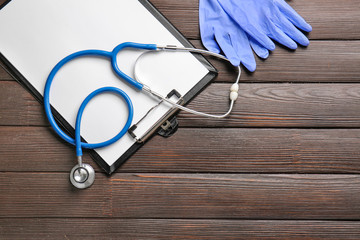 Stethoscope, clipboard and gloves on table