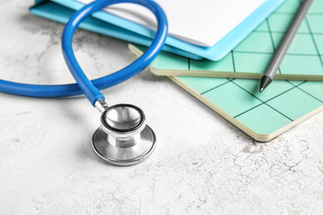 Stethoscope, clipboard and notebooks on table