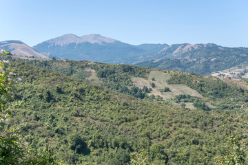 Obraz premium Sirino peak looms out of green ridge in green landscape of Southern Apennnines, near Moliterno, Italy