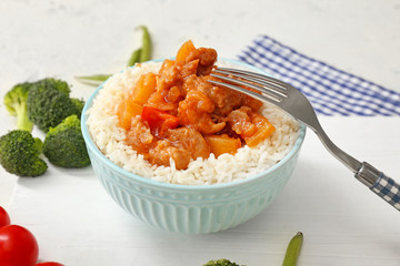 Bowl with tasty rice, chicken and vegetables on white table