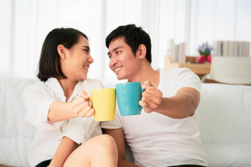 Obraz na płótnie Canvas Asian young couple enjoying together with coffee in the morning in badroom, concept of leisure, couple, relationship and valentine. Photograph with copy space