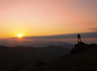 Mountaineer on a rock with the sun at sunset, Gipuzkoa from Mount Jaizkibel, Euskadi