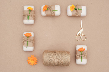 Natural handmade soap, decorated kraft paper , blue flower, skein of twine and scissors, frame border Organic cosmetics, zero waste, eco friendly concept. Top view Flat lay Copy space