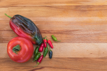 Organic tomato and peppers on a wooden cutting board