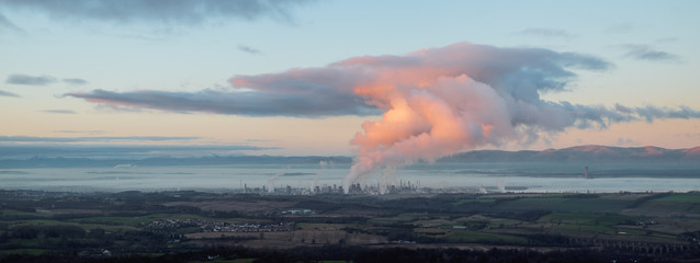 Panorama of the sea bay on which there is a large oil refinery. Smoke rises from its chimneys,...