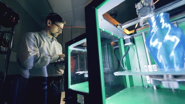 Person controls printing machines with vases. Professional industrial designer creates 3d printed product in a designing agency.