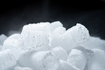 Dry ice cubes with vapor on black background.