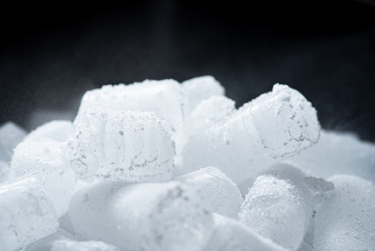 Dry ice cubes with vapor on black background.