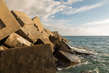 Breakwater blocks in the port of Puerto Rico, Gran Canaria, with the Atlantic Ocean in the background